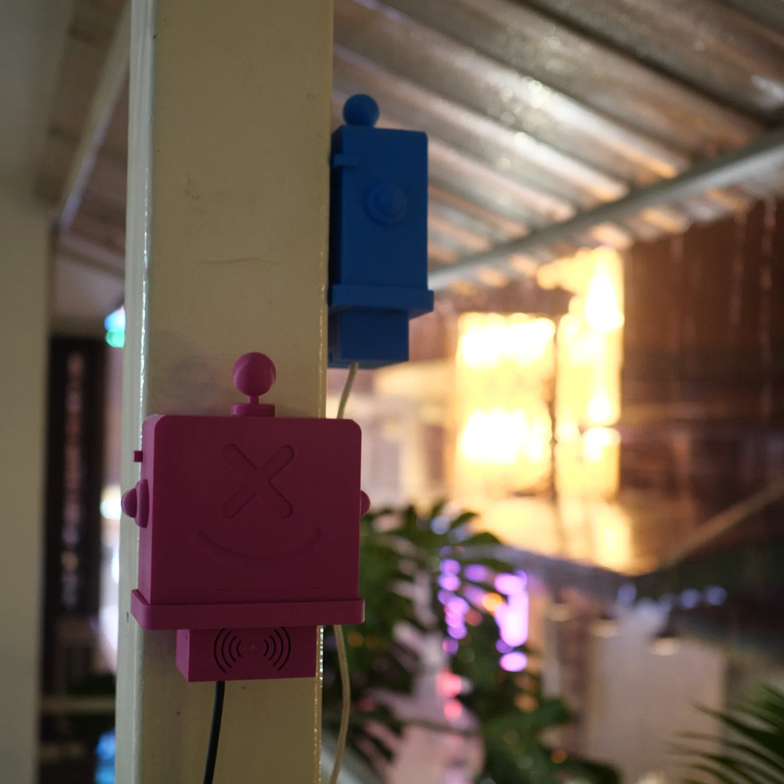A magenta Altruist on a column with warm evening shopfront light behind it