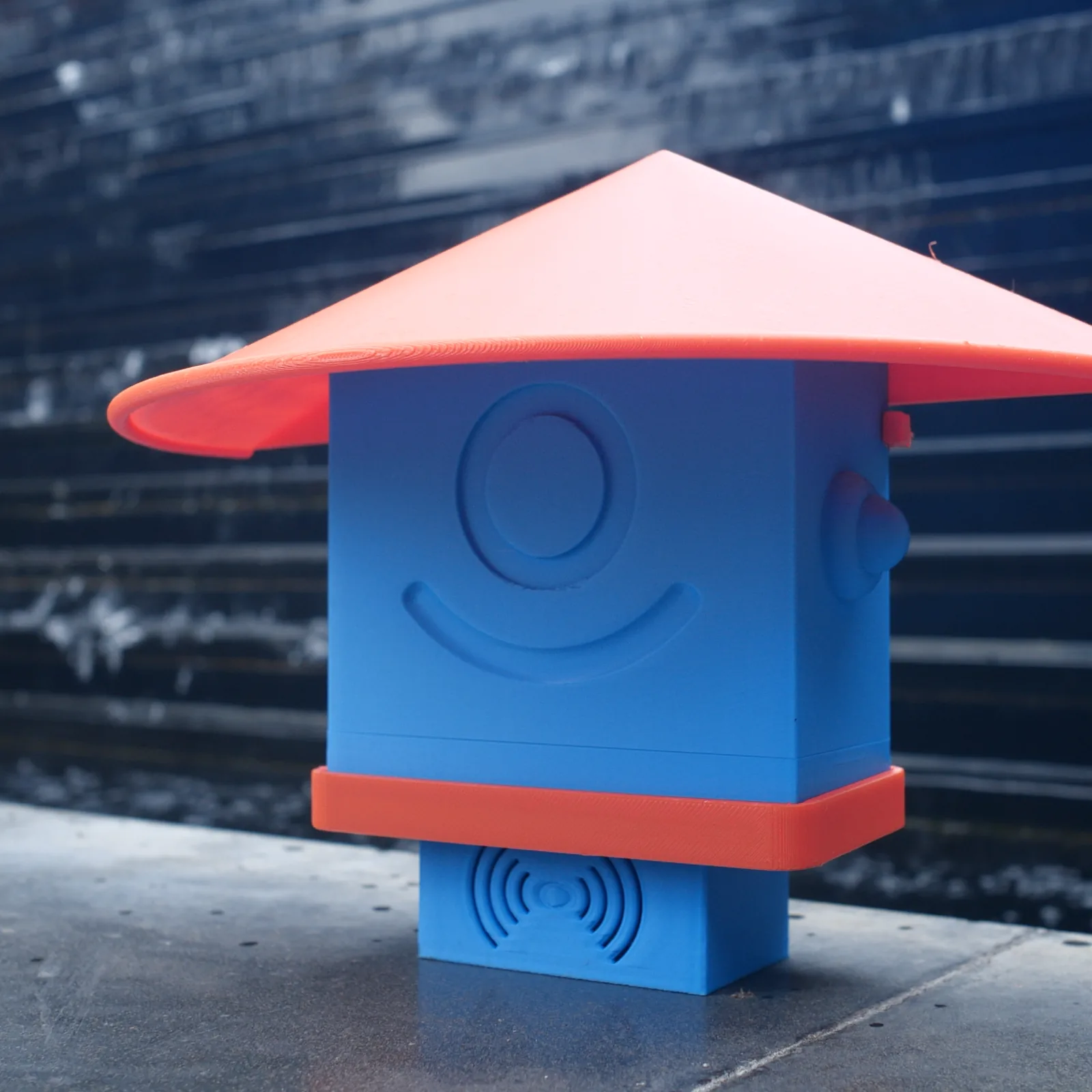 A blue Altruist standing on a kerb against a dark wall
