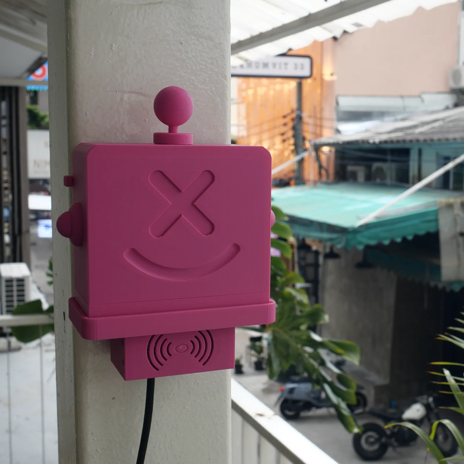 A pink Altruist on a column above a street of parked motorbikes
