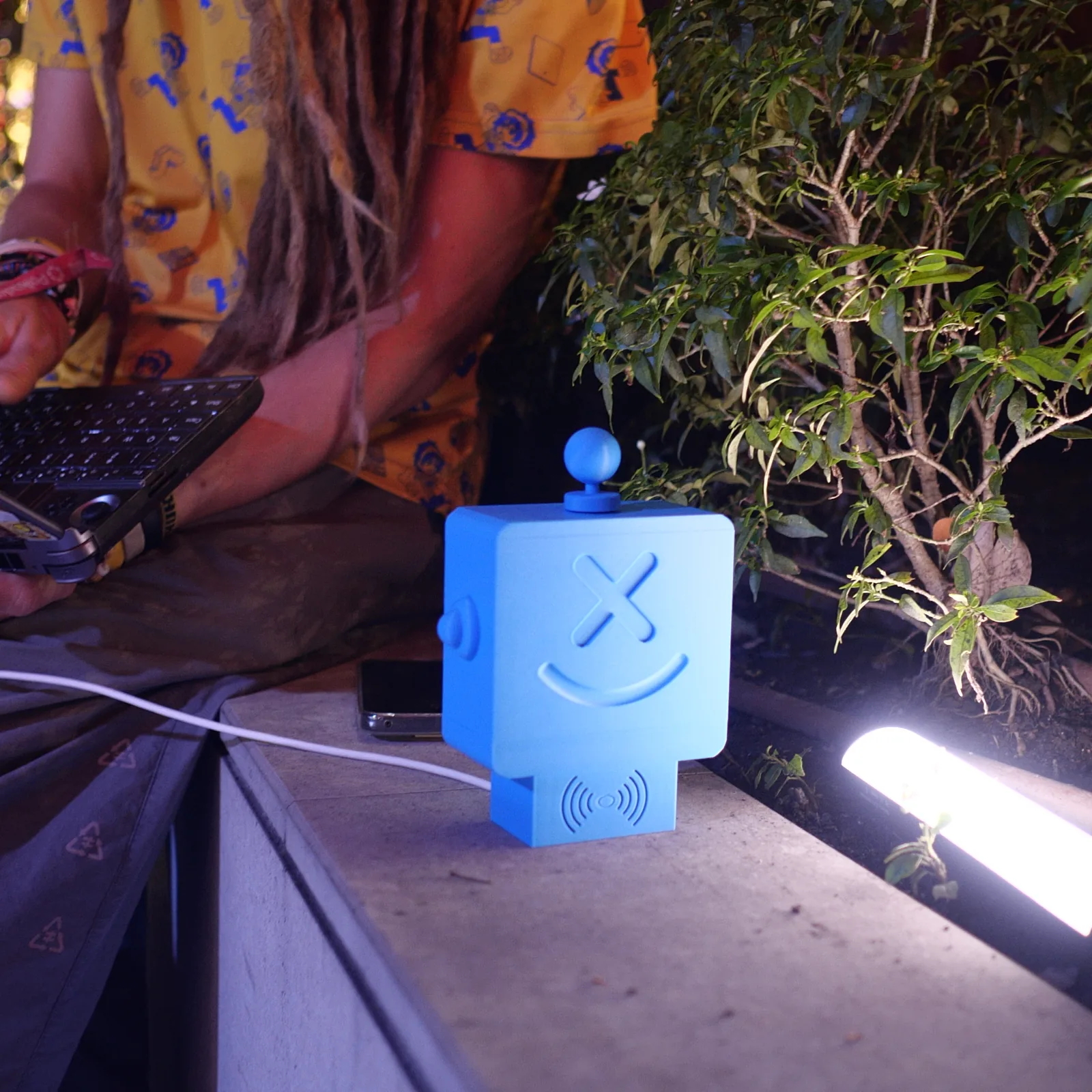 A blue Altruist on a rail at night beside someone typing on a keyboard