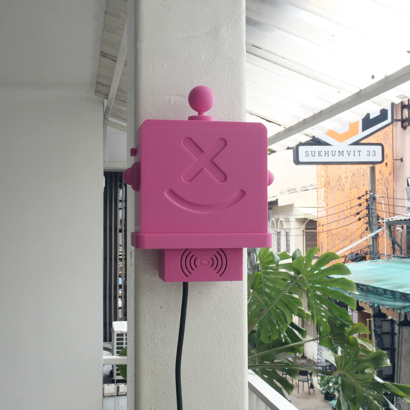 A pink Altruist mounted on a column, the Sukhumvit 33 street sign behind it